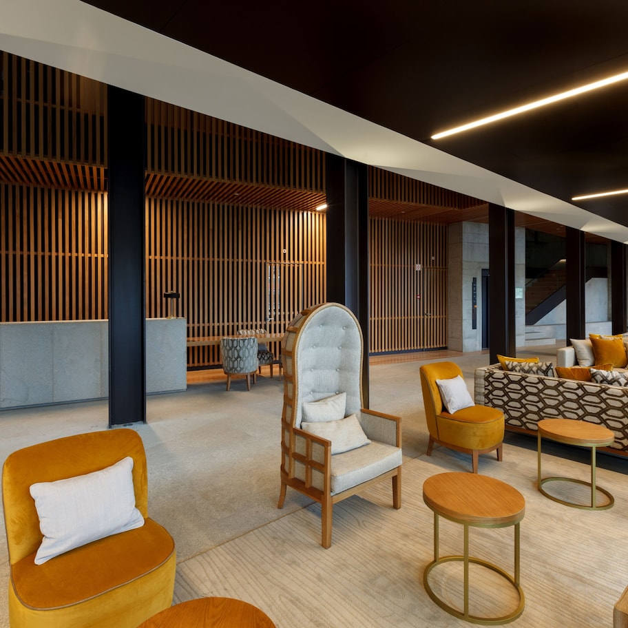 A modern lounge area with a sofa set, armchairs, and a high-back chair.