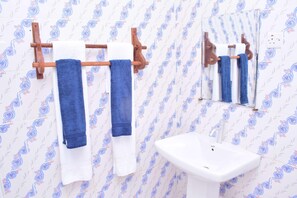 A bathroom with patterned wallpaper, a wooden towel rack with two towels, and a white sink. - Dafu Boutique Hotel Stonetown (Stonetown)