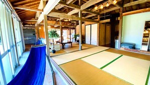 Een traditionele Japanse kamer met tatami vloeren, een blauwe hangmat en houten balken aan het plafond.