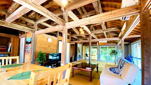 Een houten interieur met een eettafel, stoelen, een bank en een televisie.