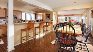 Une cuisine spacieuse avec un coin repas, comprenant une longue table en bois et plusieurs tabourets de bar.
