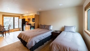 A bedroom with two beds, a dining area, and a kitchen. - Breakaway West Studio Condo with Pool and Hot Tubs by RedAwning (Vail)