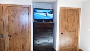A room with a wooden wardrobe, a TV on a stand, and a carpeted floor. - Breakaway West Studio Condo with Pool and Hot Tubs by RedAwning (Vail)