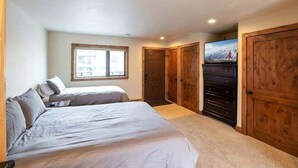 A bedroom with two beds, a wooden dresser, and a TV. - Breakaway West Studio Condo with Pool and Hot Tubs by RedAwning (Vail)