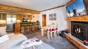 A modern kitchen with wooden cabinets, a dining area with a table and chairs, and a fireplace.
