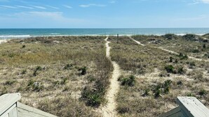 A beach path leading to the ocean with sparse vegetation and a clear sky. - Lime Inn 4 Bedroom Home by RedAwning (Supply)