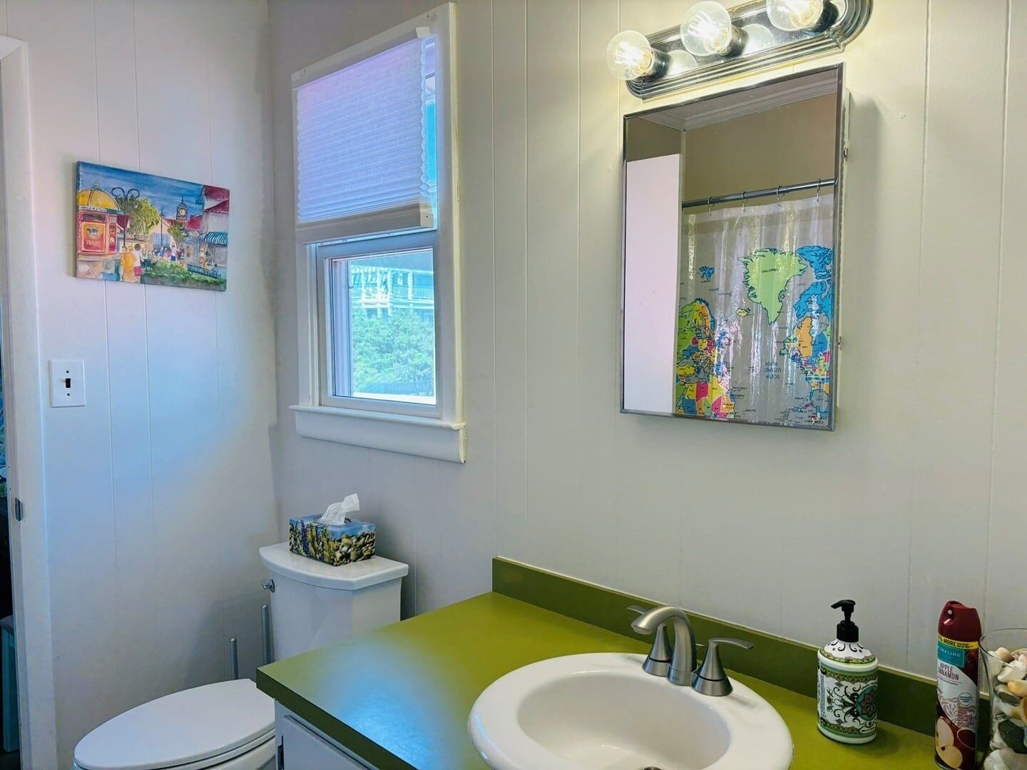 A bathroom with a toilet, sink, and window with blinds.