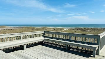 A wooden deck with a railing overlooking a beach.