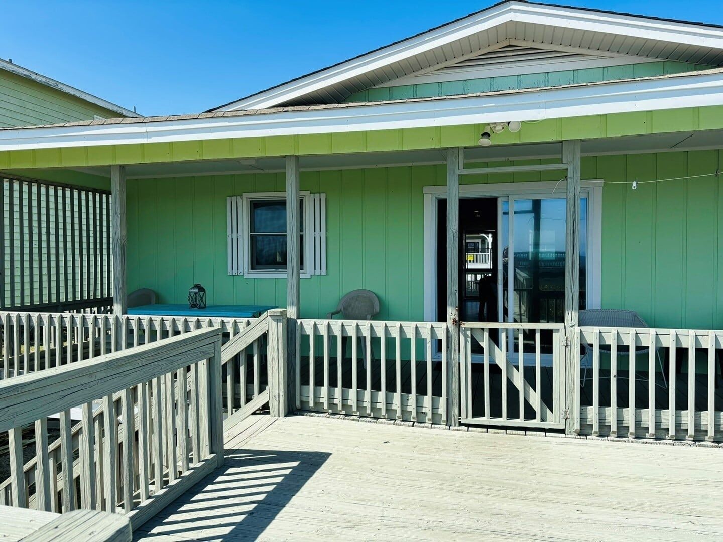 A green building with a covered porch and a wooden deck.