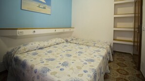 A room with two beds, a painting of a beach scene, a wooden shelf unit, and a patterned carpet. - Apartment in Villa Valentini, seafront, Gulf of Gaeta, parking included (Marina di Minturno)