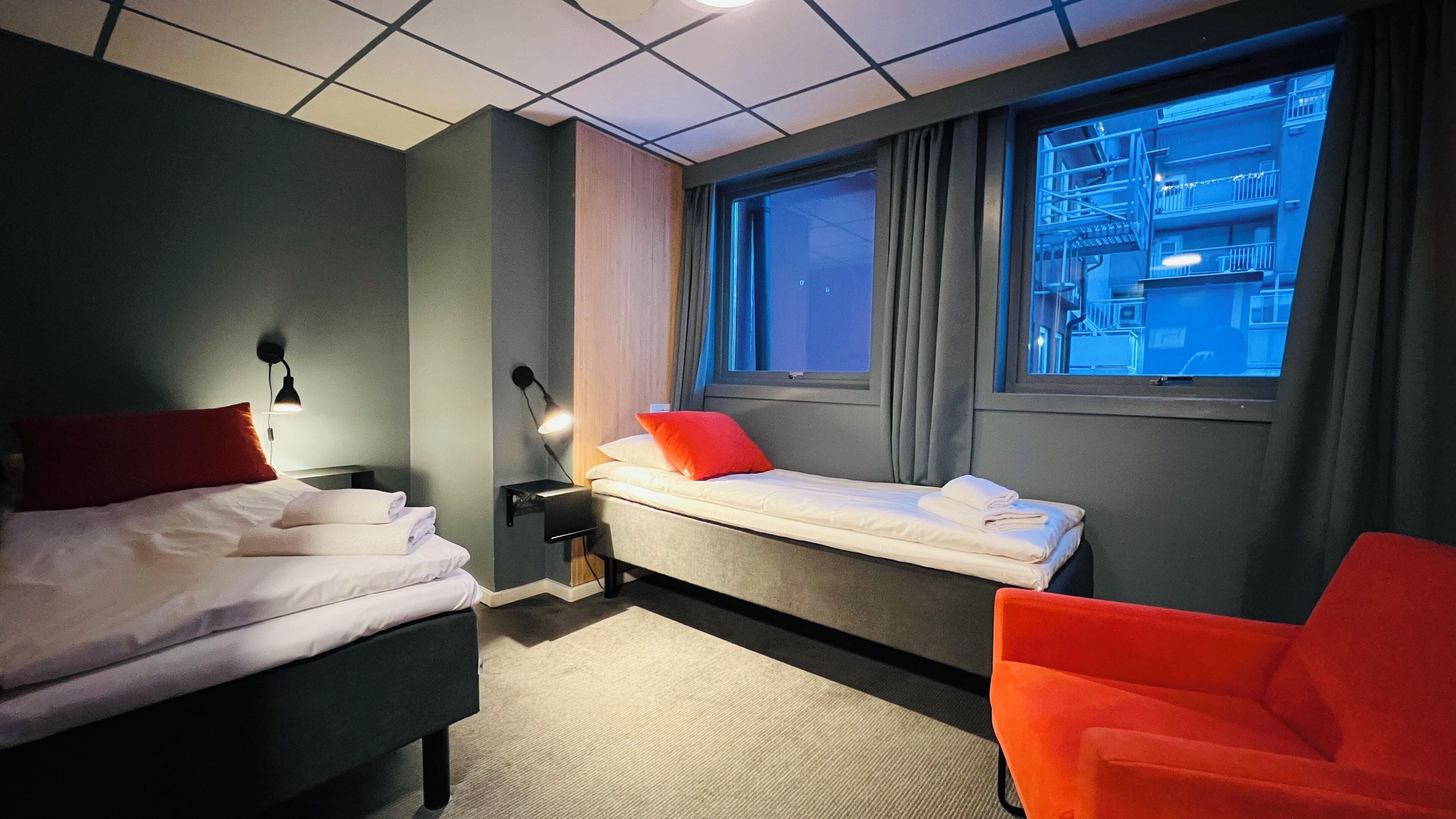 Een hotelkamer met een bed, een klein bureau, een stoel en een raam met gordijnen.