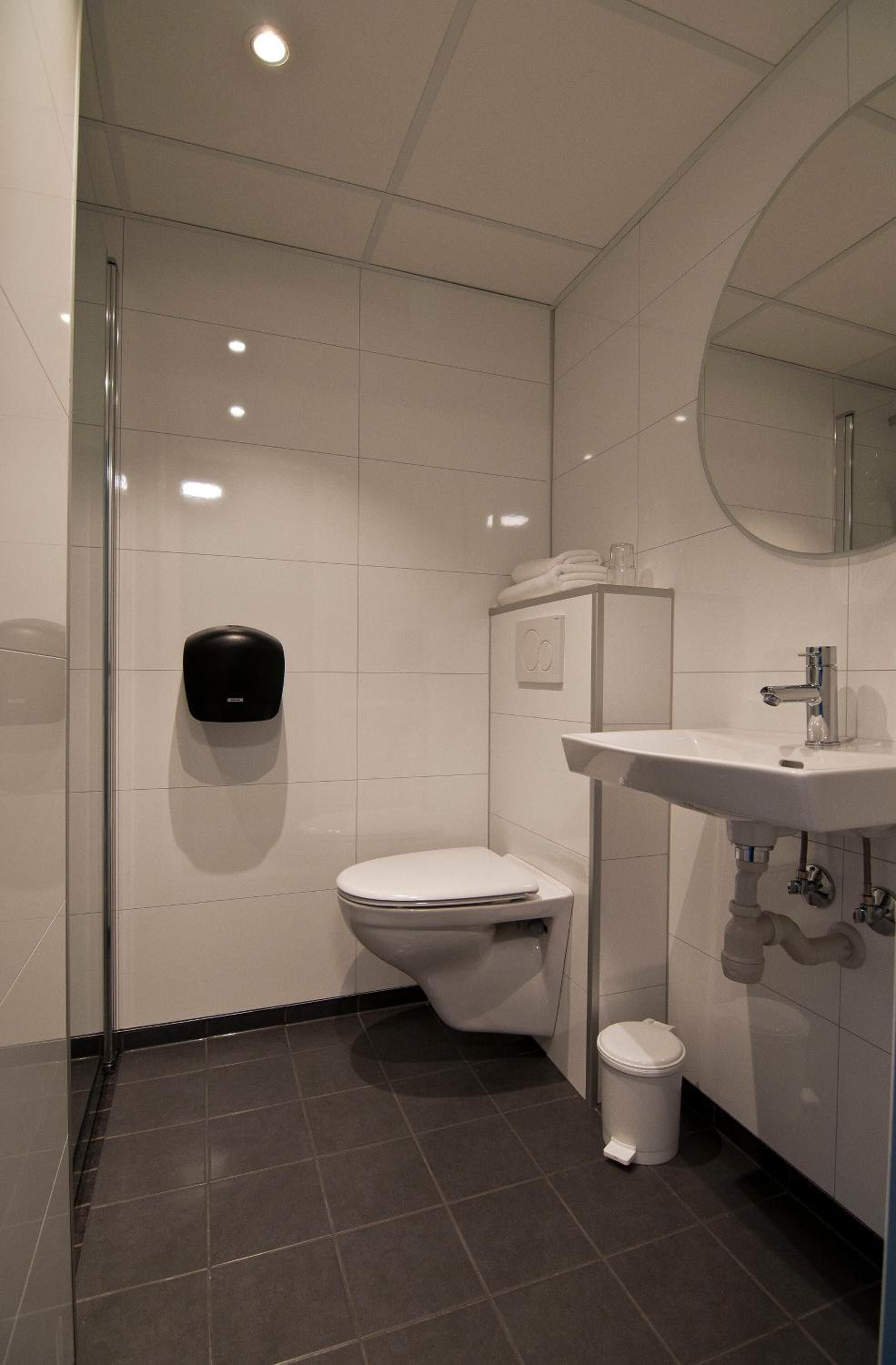 A modern bathroom with a toilet, sink, and hand dryer.