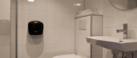 A modern bathroom with a toilet, sink, and hand dryer.