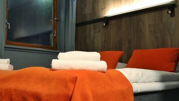 A hotel room with a bed, a window, and a wall-mounted light fixture.