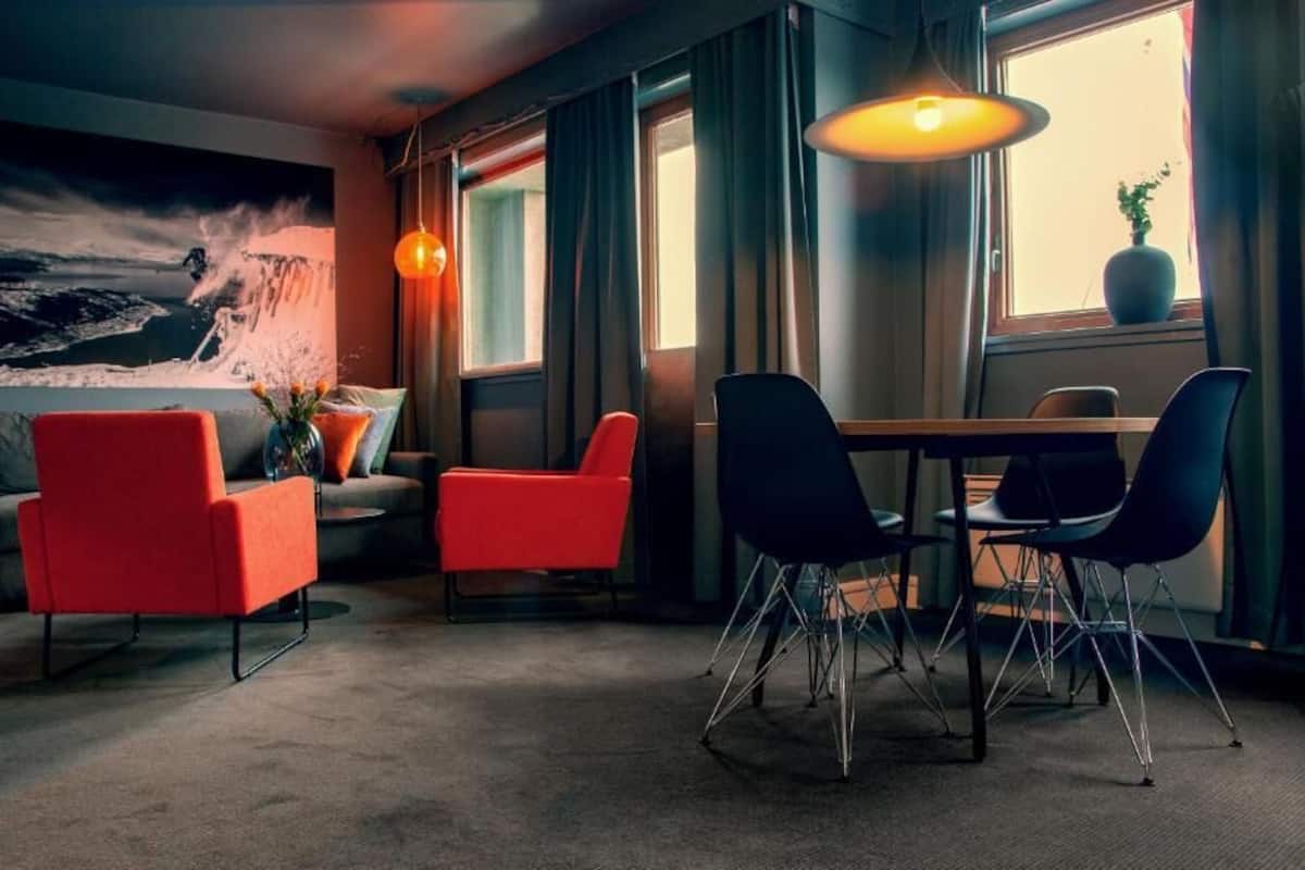 A modern room with a large window, a dining table with chairs, and a sofa.