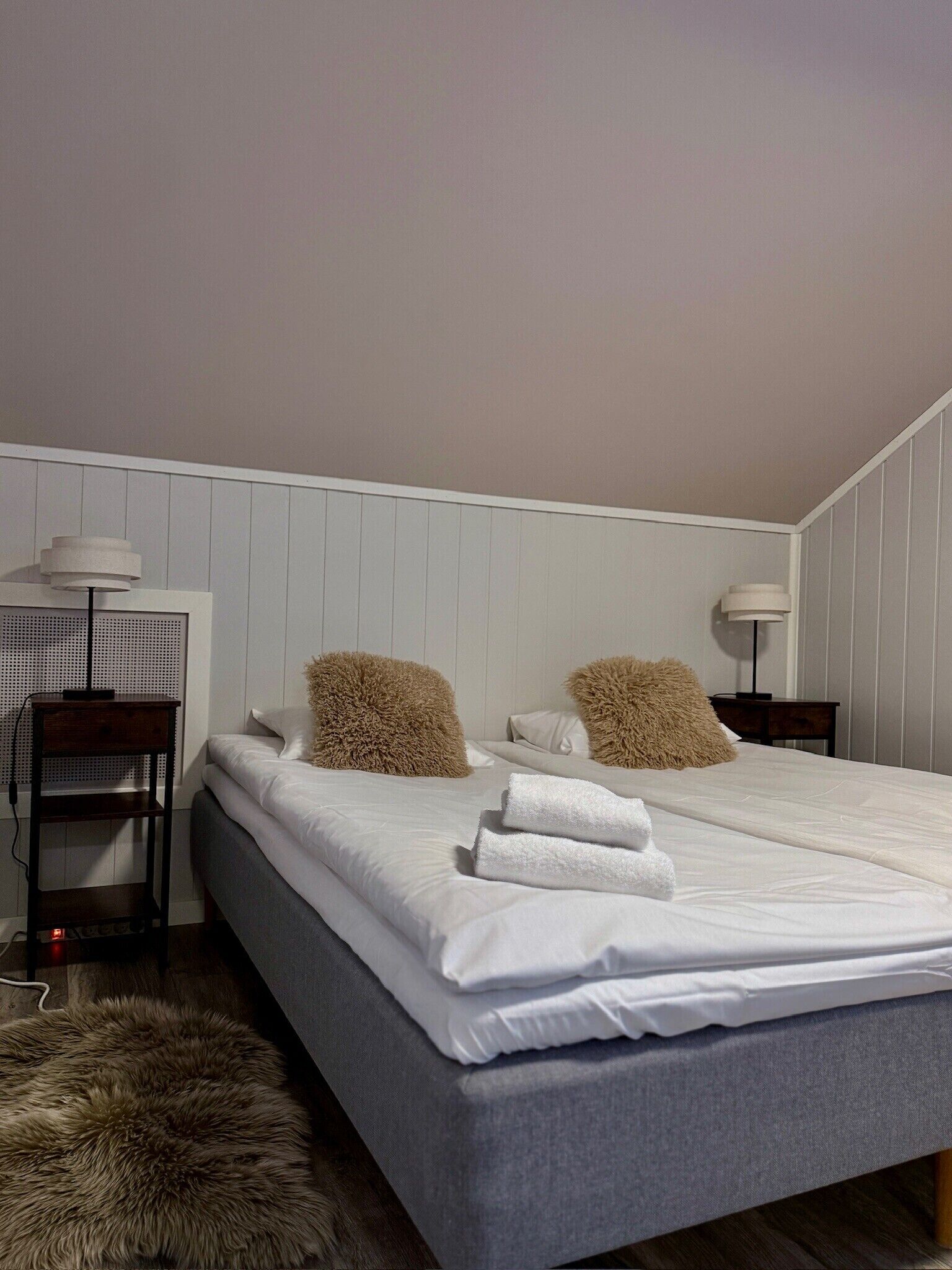 A bedroom with a bed, two nightstands, a desk, and a lamp.