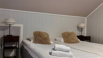 A bedroom with a bed, two nightstands, a desk, and a lamp.
