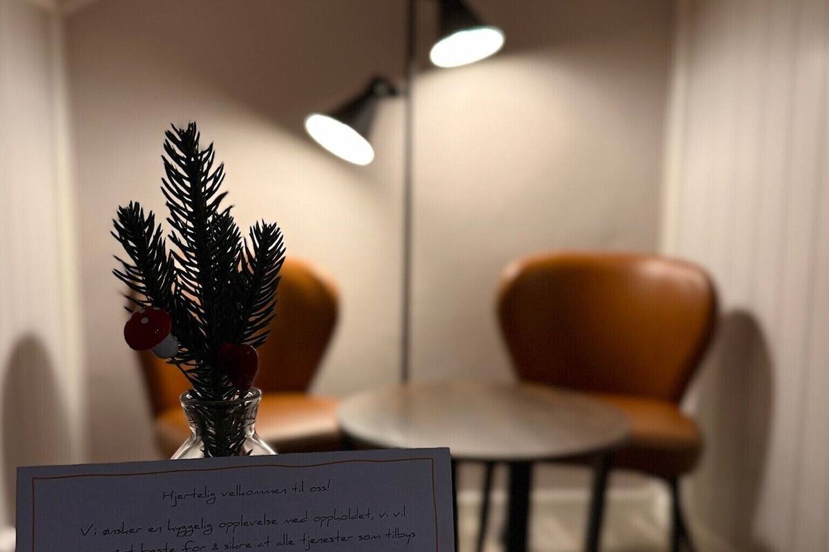 A dining area with a small table and two chairs, a Christmas tree, and a sign with text.