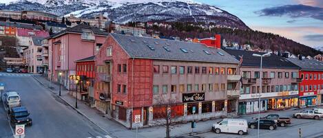 A hotel with a sign reading "Narvik Hotel" in a town with a mountain backdrop.