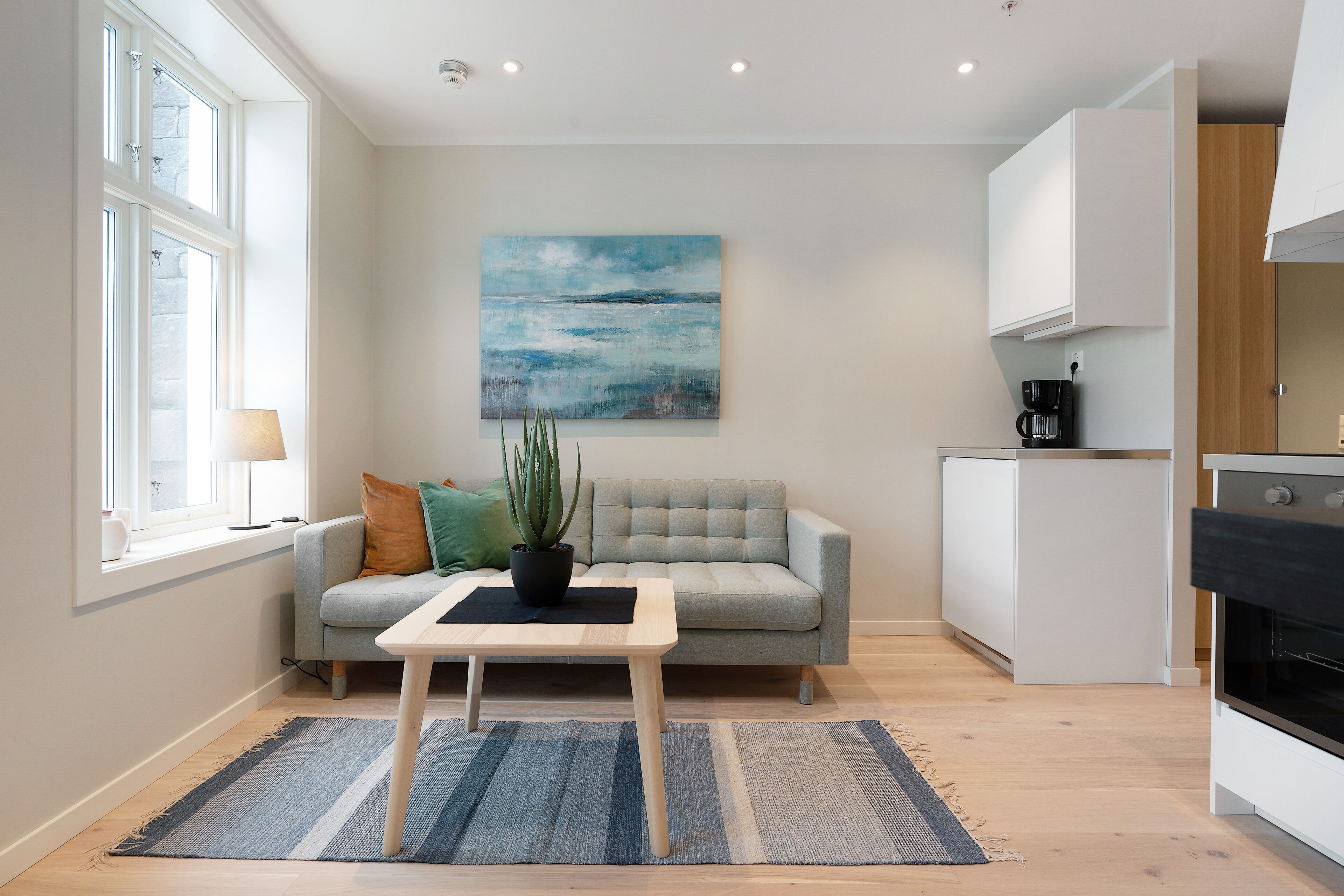 A modern living room with a sofa, a coffee table, and a painting on the wall.