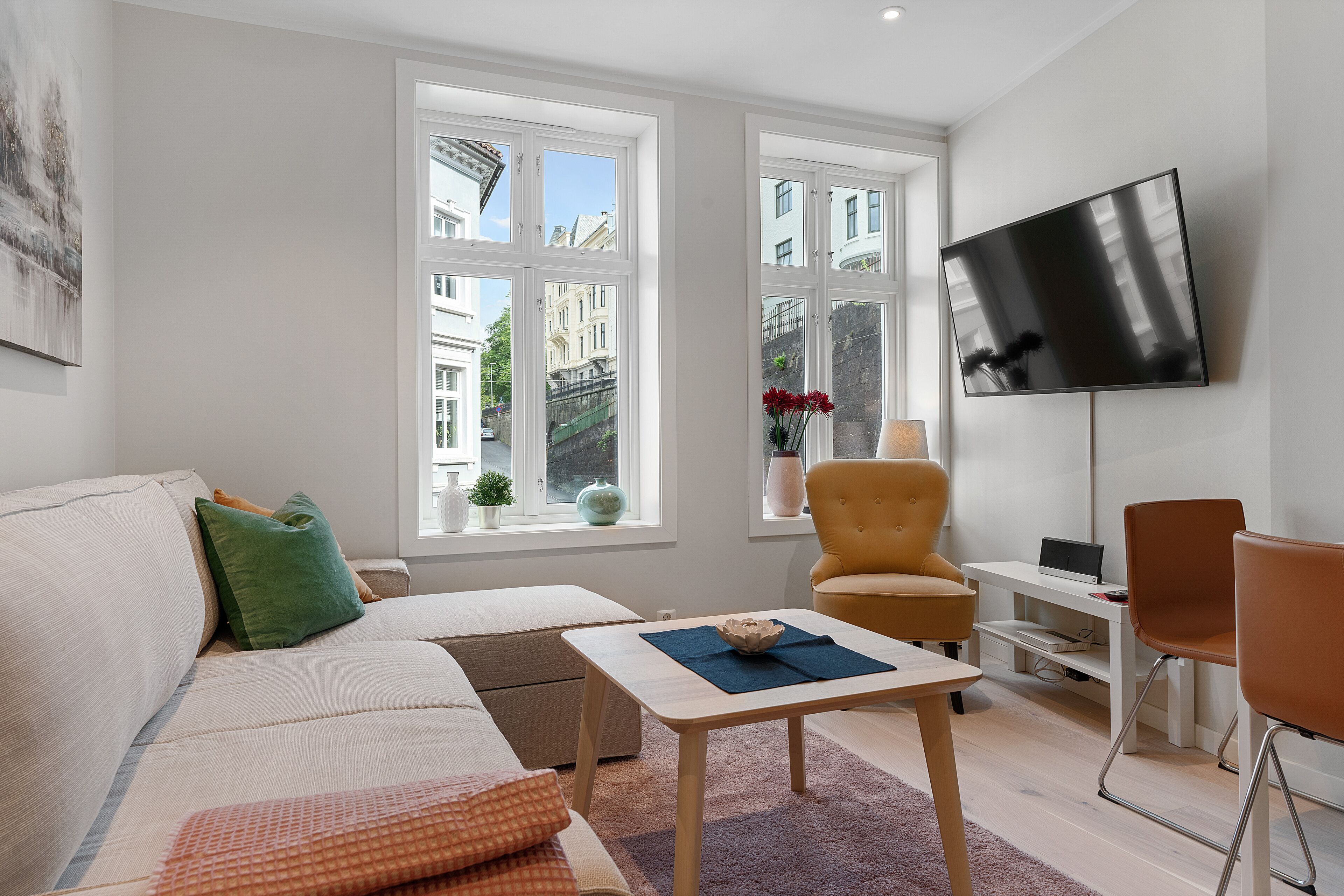 Una sala de estar moderna con un sofá, sillones, una mesa de centro y un televisor montado en la pared.