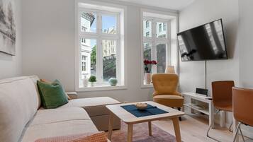 Una sala de estar moderna con un sofá, sillones, una mesa de centro y un televisor montado en la pared.