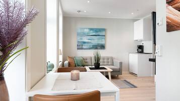 A modern living room with a dining table, sofa, and a painting on the wall.