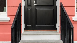 A black door with a glass panel, white steps, and black railings. - Barfot Apartments (Bergen)