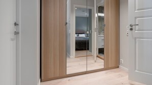 A modern bedroom with a large wardrobe, a bed, and a mirror. - Barfot Apartments (Bergen)