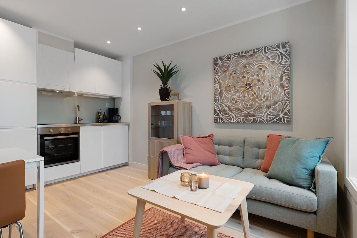 A modern kitchen with white cabinets, a built-in oven, and a dining area with a table and chairs.