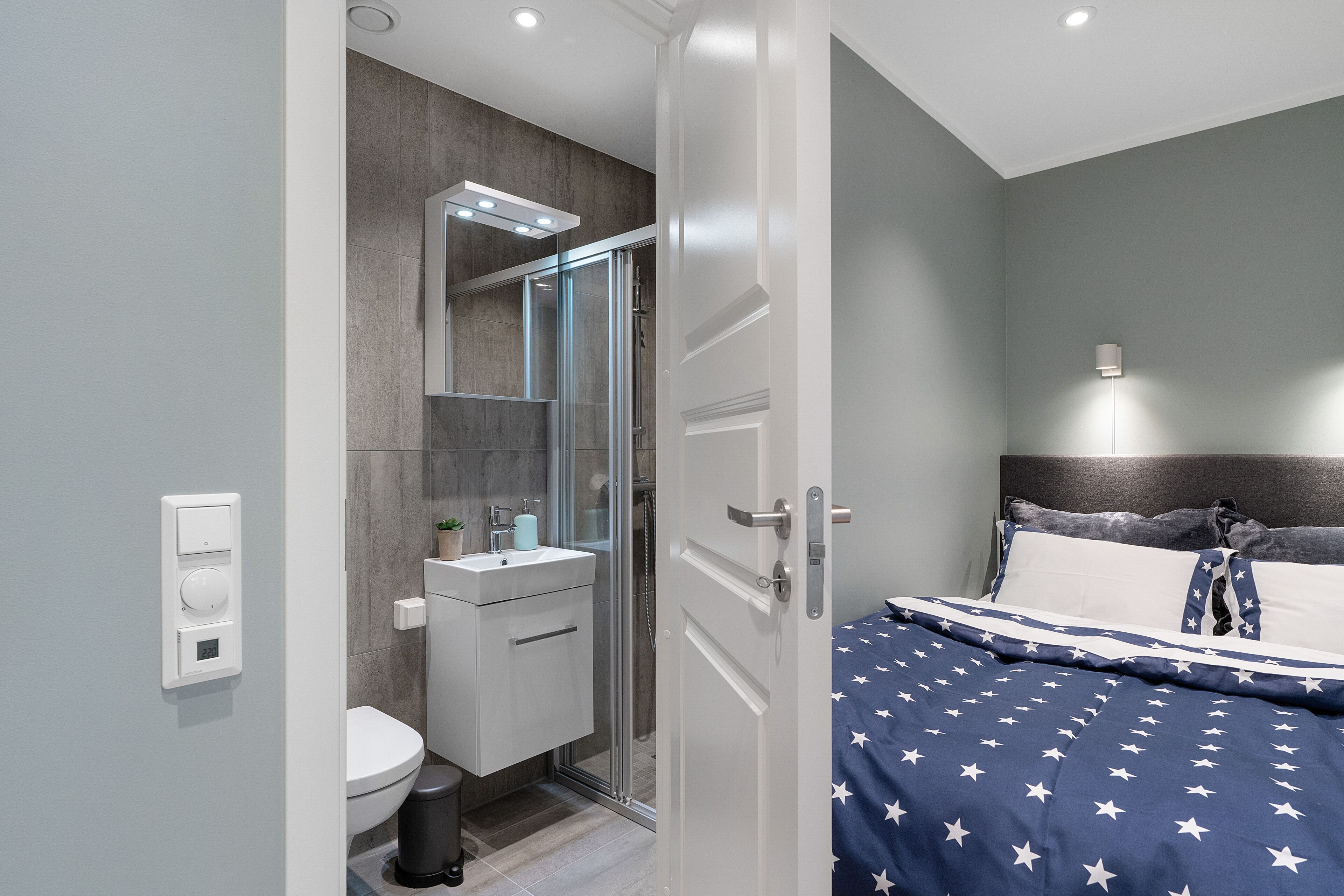 A modern bathroom with a glass shower enclosure, a white toilet, and a sink with a mirror above it.