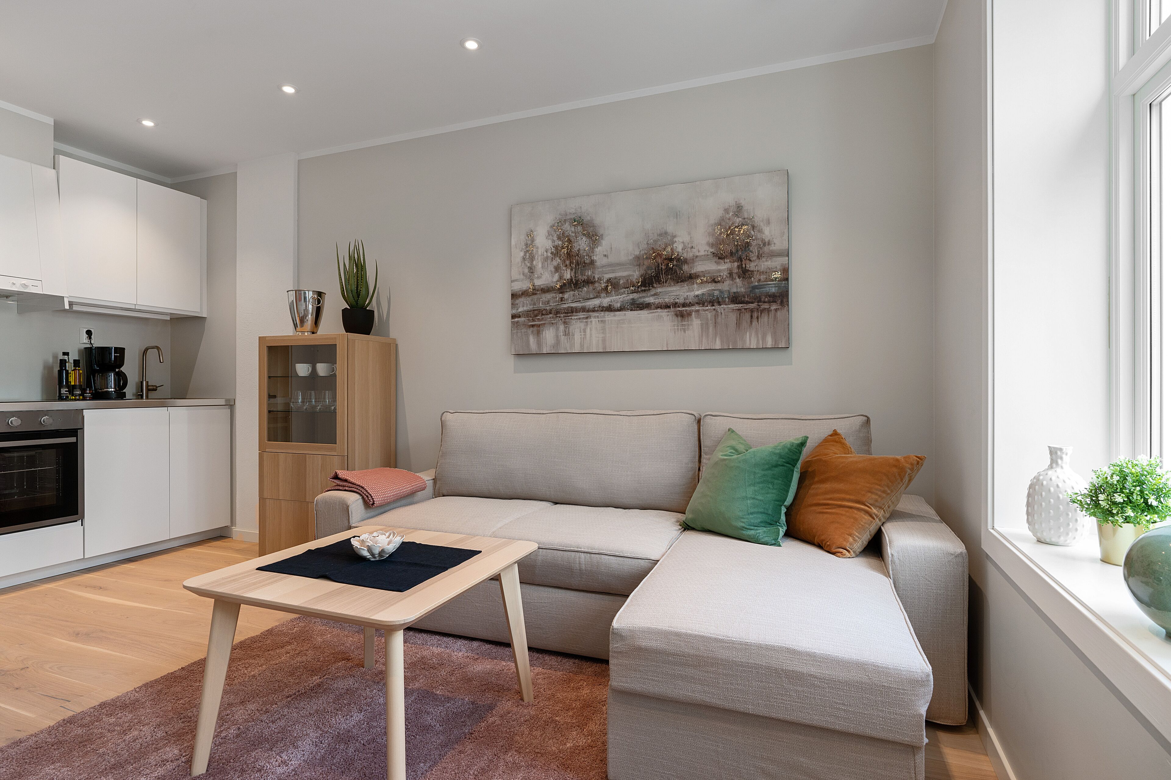 Un salon moderne avec un canapé, une petite table et une cuisine en arrière-plan.