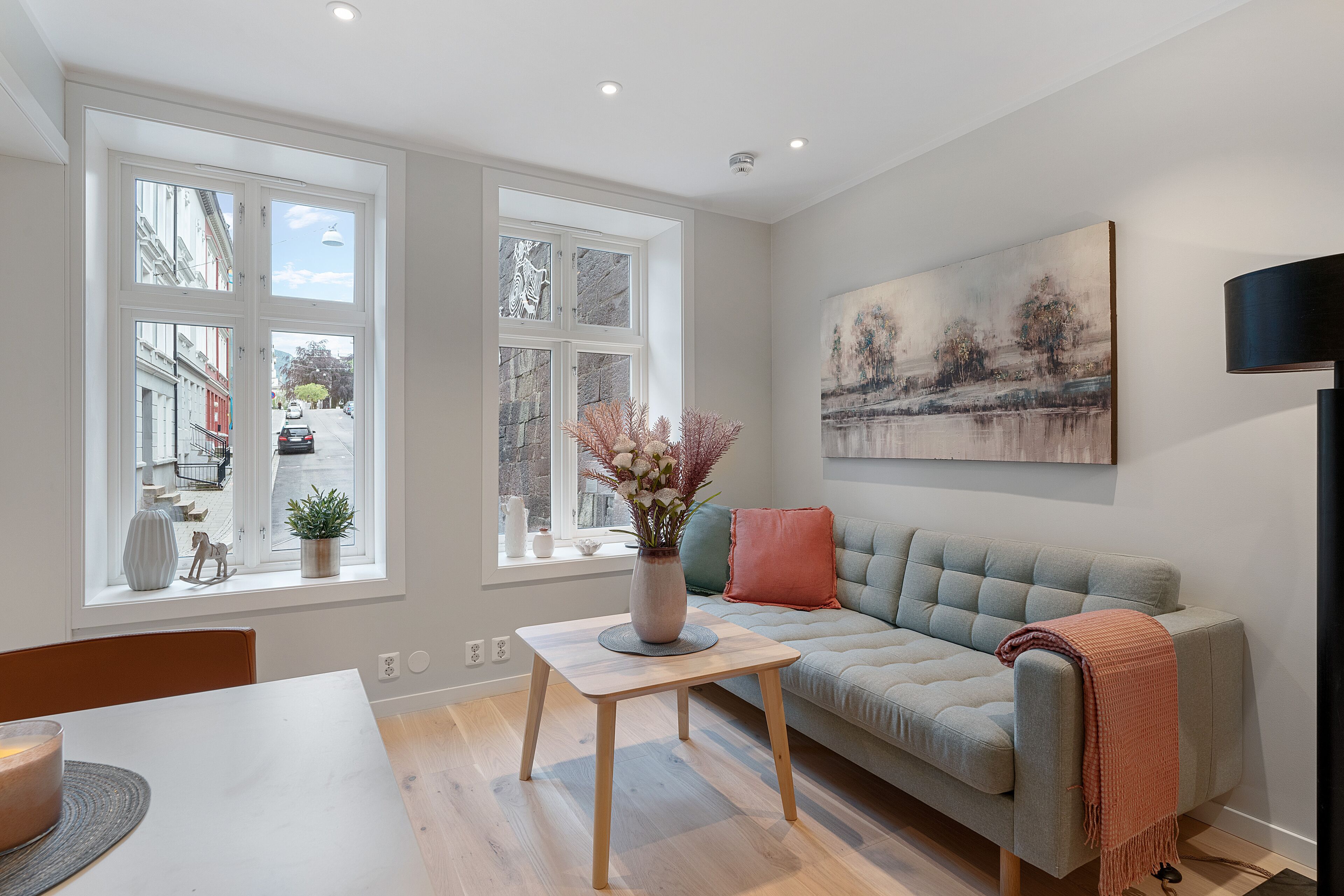 Een moderne woonkamer met een bank, een tafel en een vaas met bloemen.