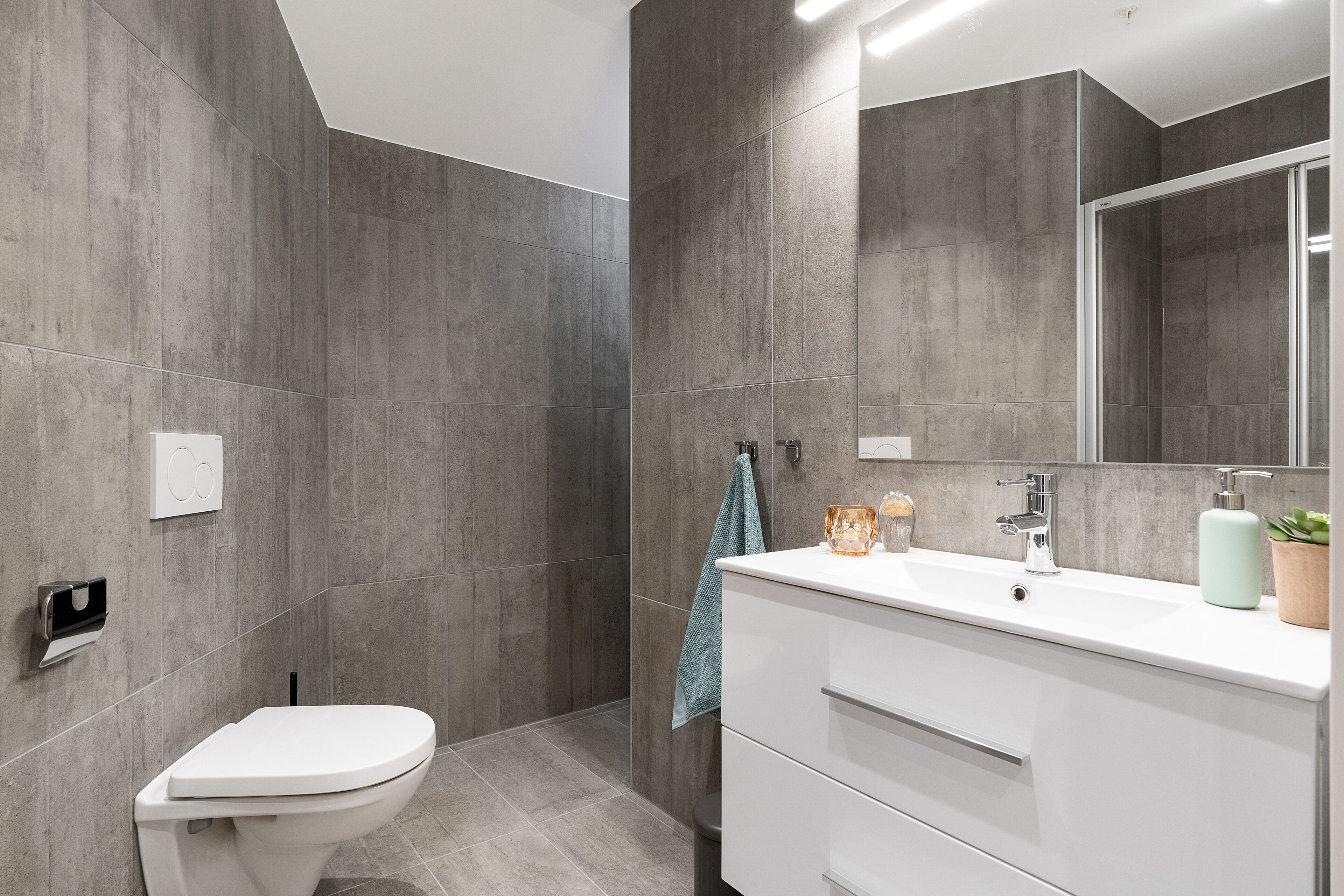 Un baño moderno con inodoro, lavamanos y zona de ducha.