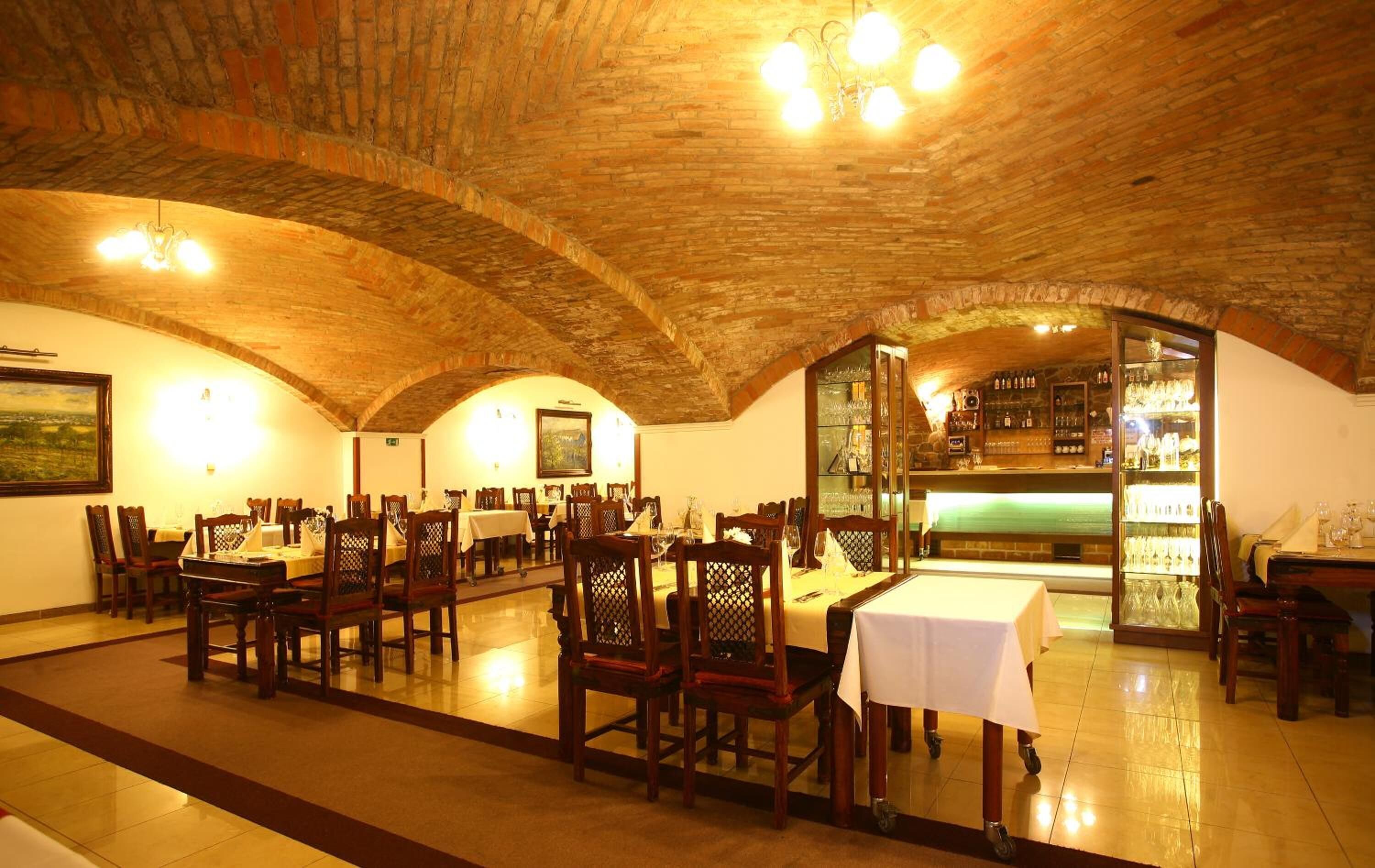 Un restaurant avec des arches en briques, des tables et des chaises en bois.