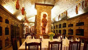 A restaurant with brick walls, a central statue, wine racks, and tables set for dining. - Garni hotel Matysak (Bratislava)