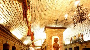 A wine cellar with brick walls, wooden racks for wine bottles, and a statue of a man holding a grapevine. - Garni hotel Matysak (Bratislava)