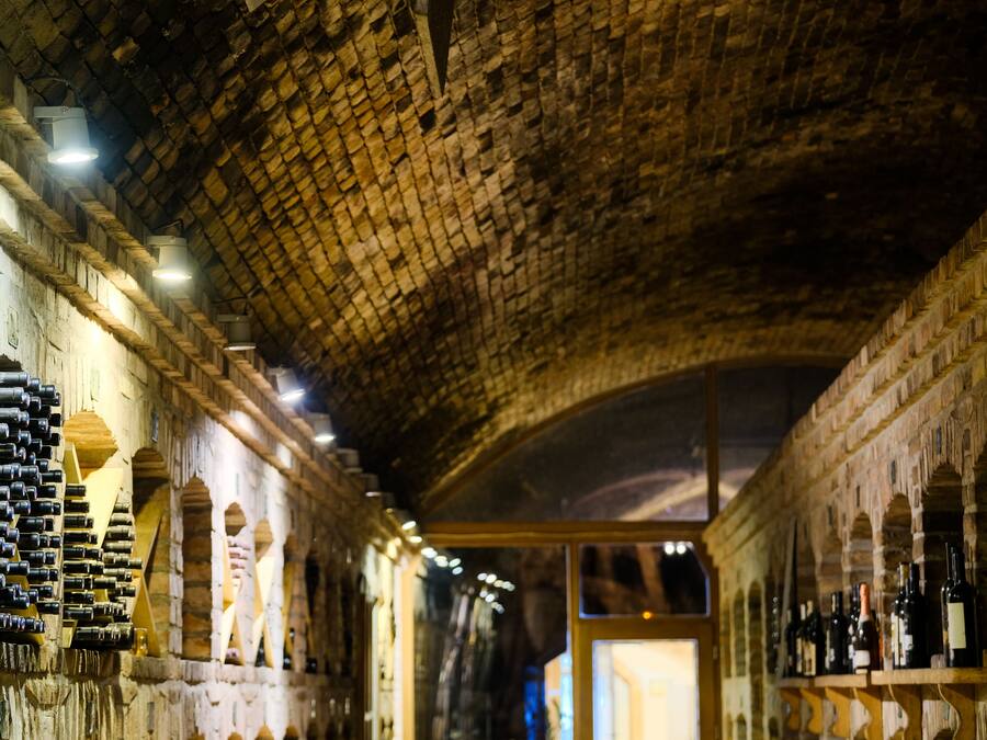 A wine cellar with wooden racks and stone walls.