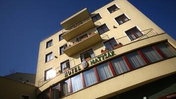 A multi-story hotel with balconies, a visible logo, and a restaurant sign.