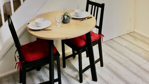 Un comedor con una mesa redonda, dos sillas, una pequeña planta en maceta y un juego de tazón y vaso.