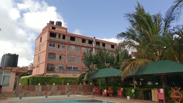 Un hôtel doté d’une piscine, de chaises rouges et de palmiers.