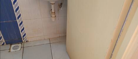 Un baño pequeño con un lavamanos blanco, una pared con azulejos blancos y azules, y un piso con pisos blancos.