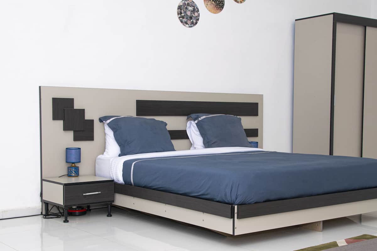 A modern bedroom with a bed, nightstand, and wardrobe.