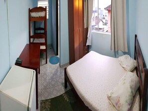 A small bedroom with a single bed, a desk, a chair, and a wardrobe. - Hostel Suarão (Itanhaém)