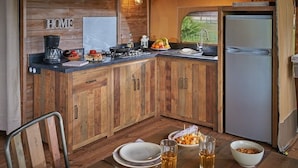 Una cucina compatta con mobili in legno, una macchina da caffè, un lavandino e un frigorifero.