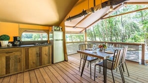 Un patio in legno con tavolo e sedie, un barbecue e un frigorifero.