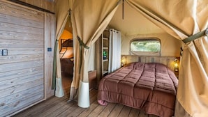 Una stanza accogliente con tenda, un letto, una finestra e una porta di legno.