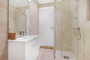 A modern bathroom with a white vanity, a glass shower enclosure, and a tiled floor.