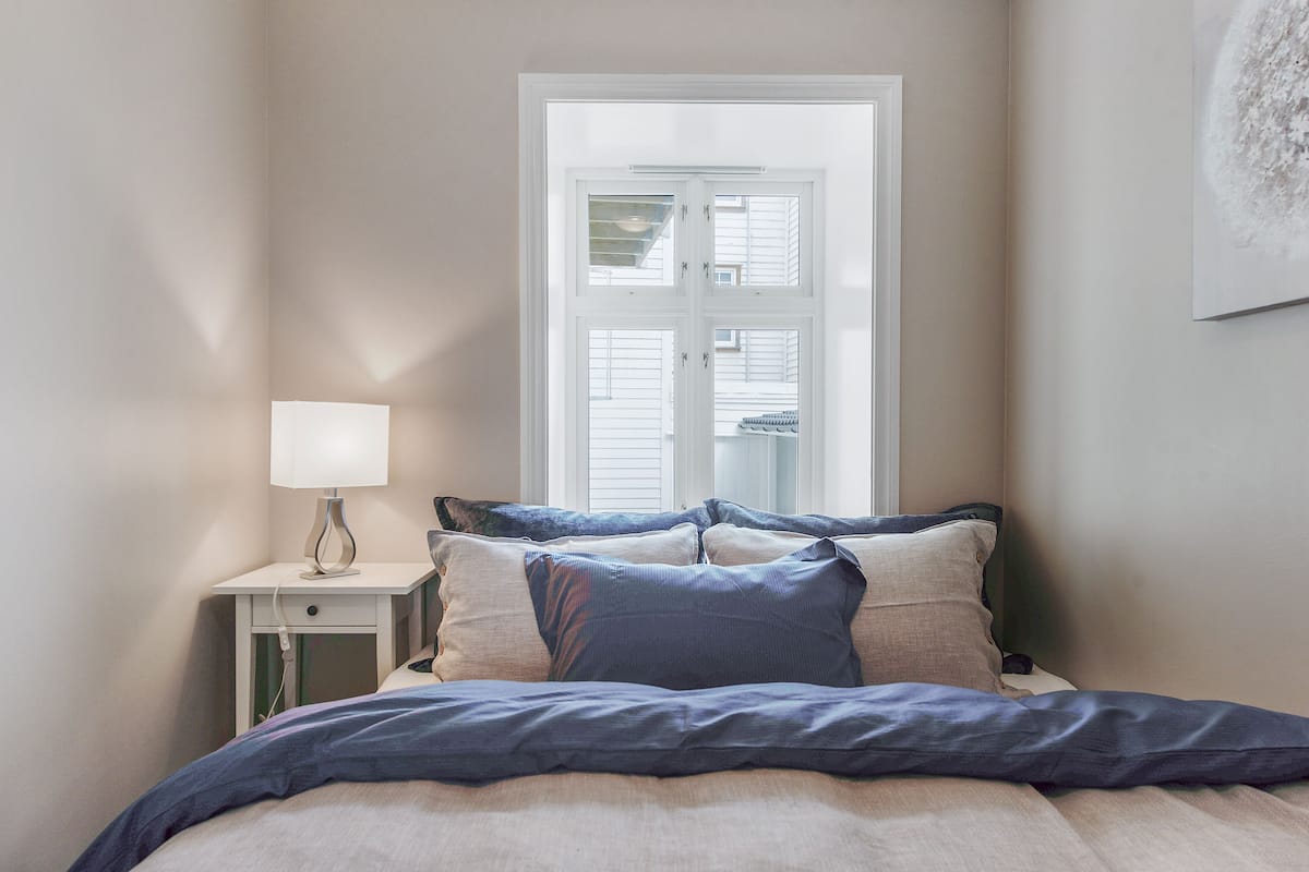 Um quarto com uma cama, uma mesa de cabeceira com abajur e uma janela com persianas.