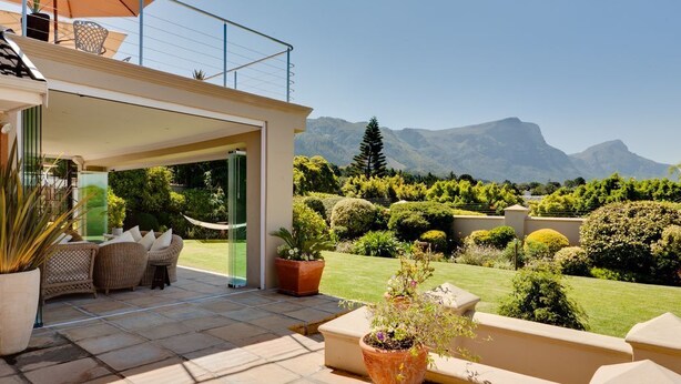 A patio area with outdoor furniture, a potted plant, and a view of a mountainous landscape. - Lime Cottage (Bel Ombre)